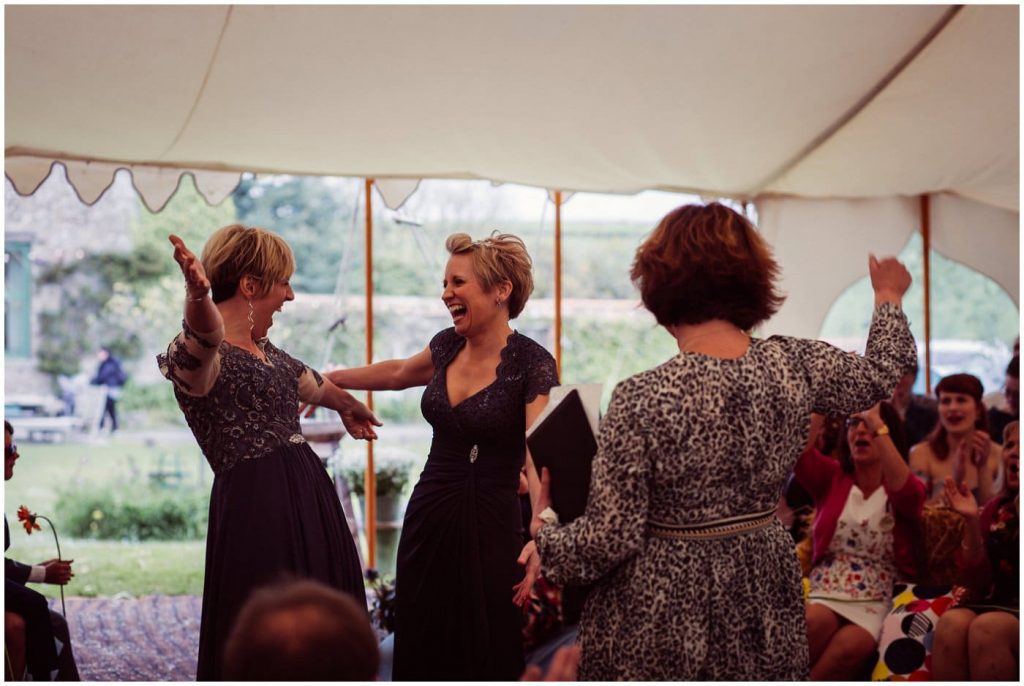 Celebrating amazing women - 2 brides in aubergine dresses celebrate with Fan at their ceremony
