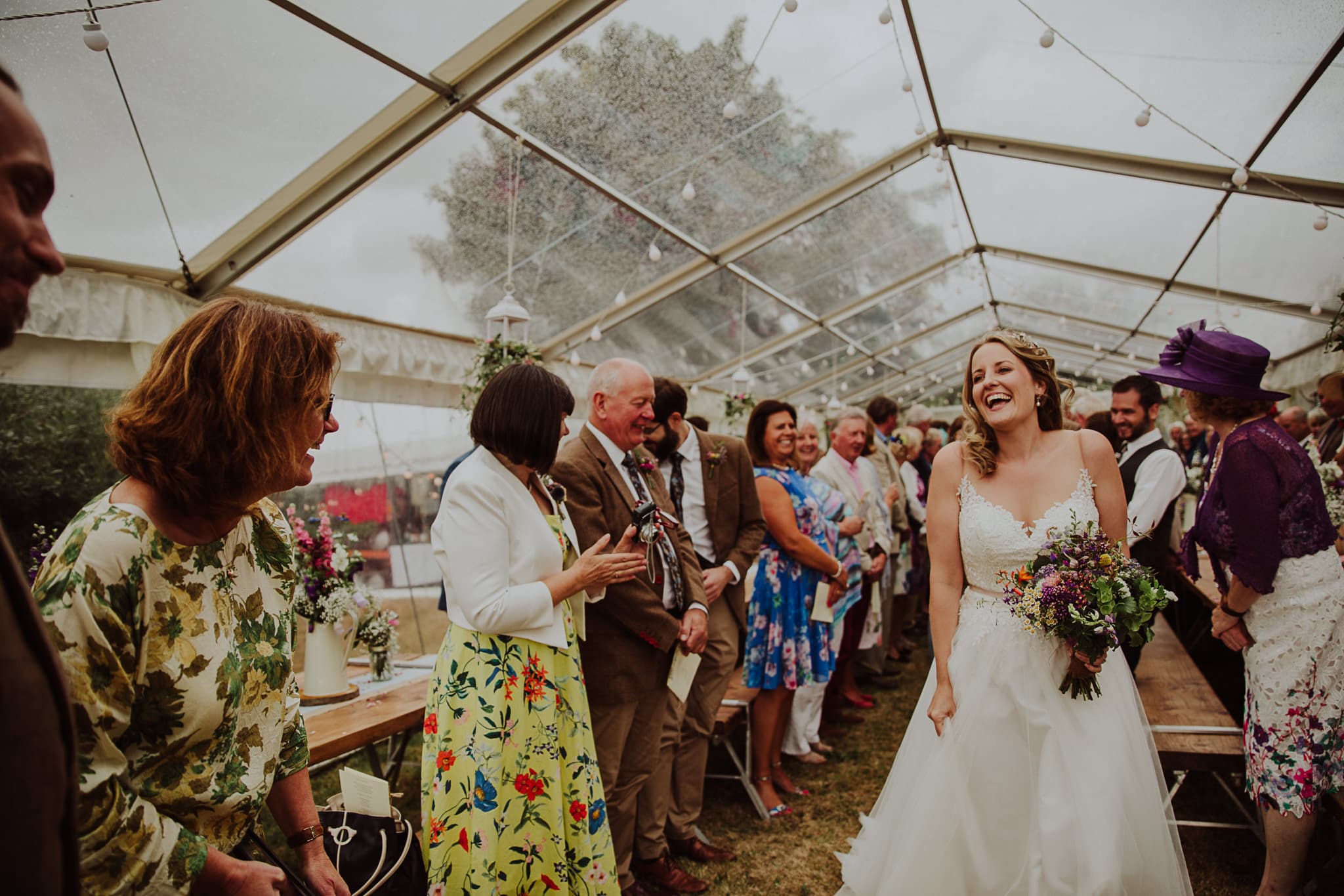 A bride laughing with Fan with her family behind her. The joys of working with a wedding celebrant