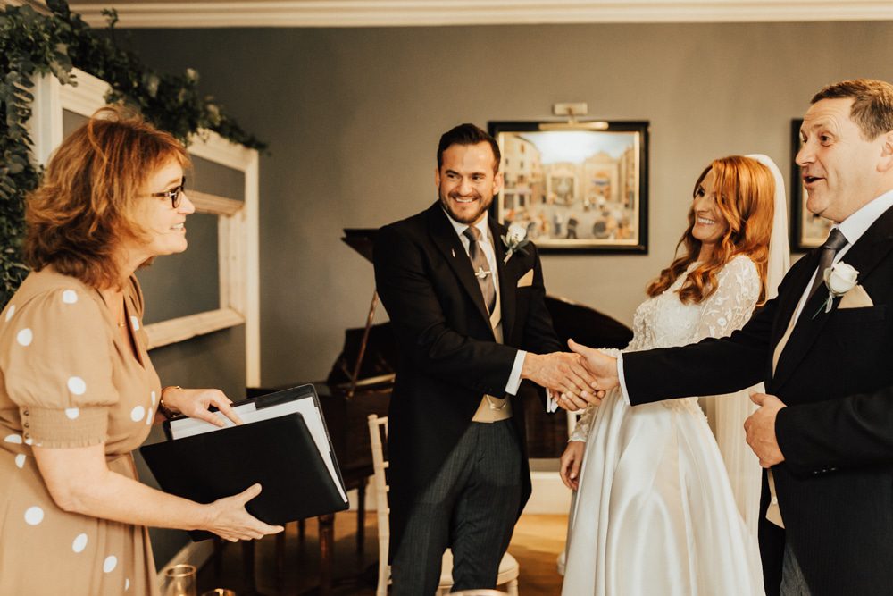 Working with a wedding celebrant, the bride's dad shakes hands with the groom after leading her to the ceremony with Fan