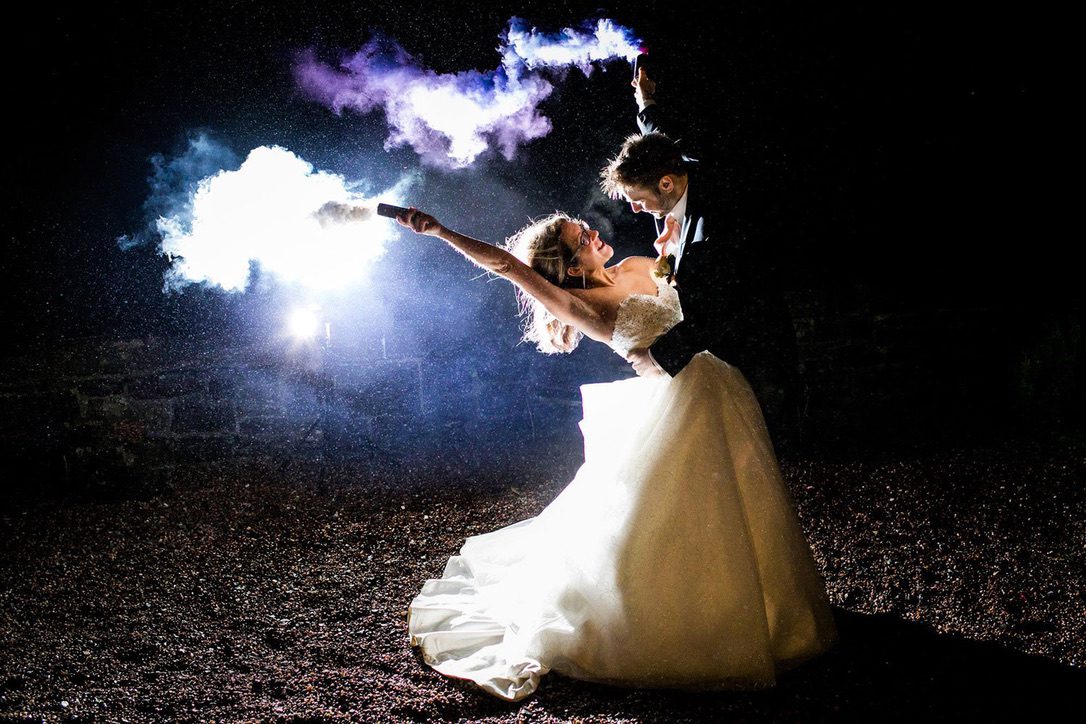 a bride and groom in the night holding flares, taken by wedding photographer