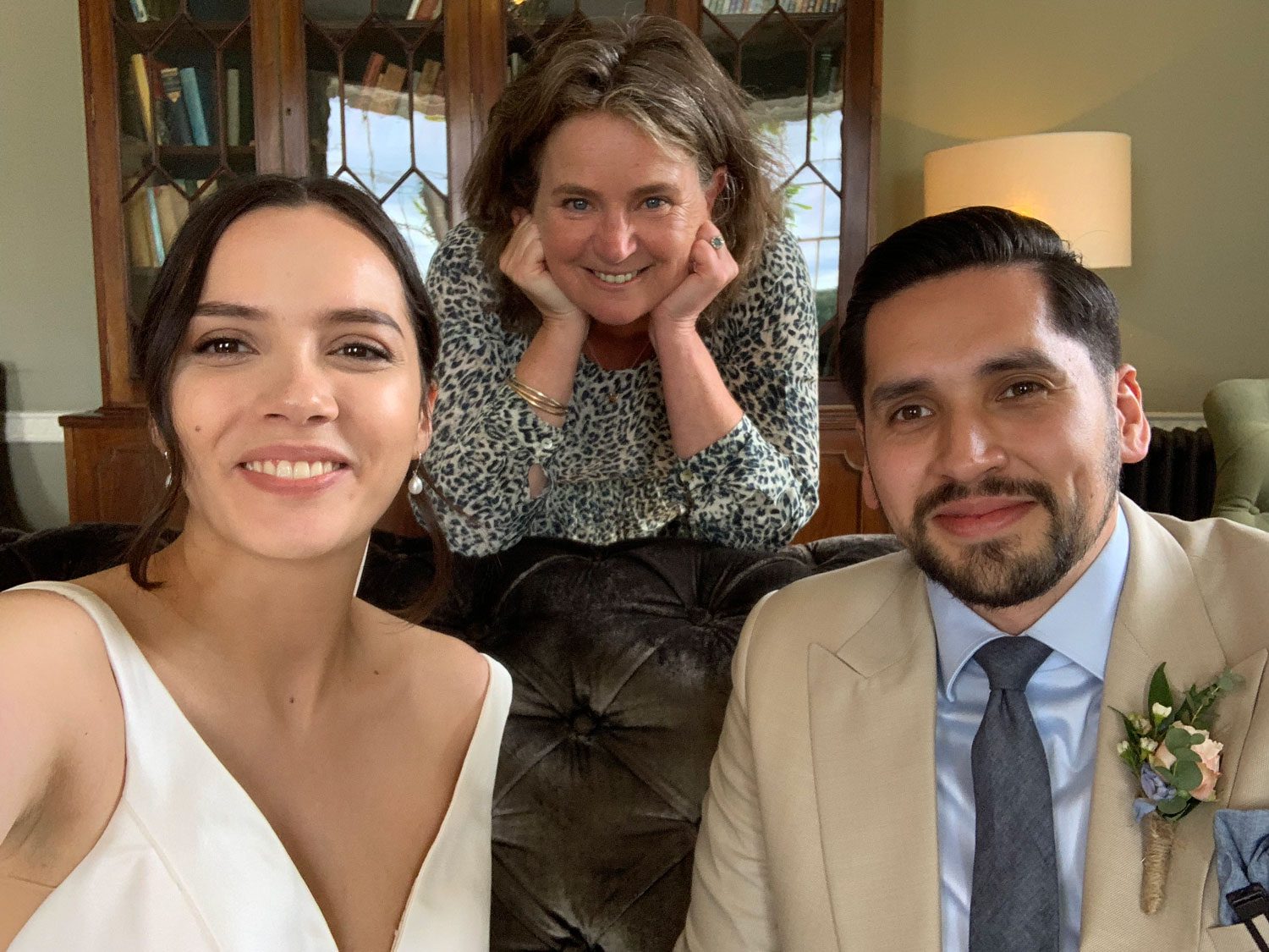 A registrar or a Celebrant - a bridal couple are sitting on a sofa with Celebrant Fan peeping between them