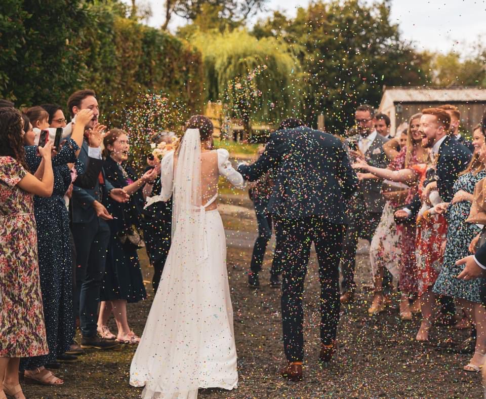 Wedding ceremony location can be your home or garden, like this bridal couple walking through their guests, showered in confetti.