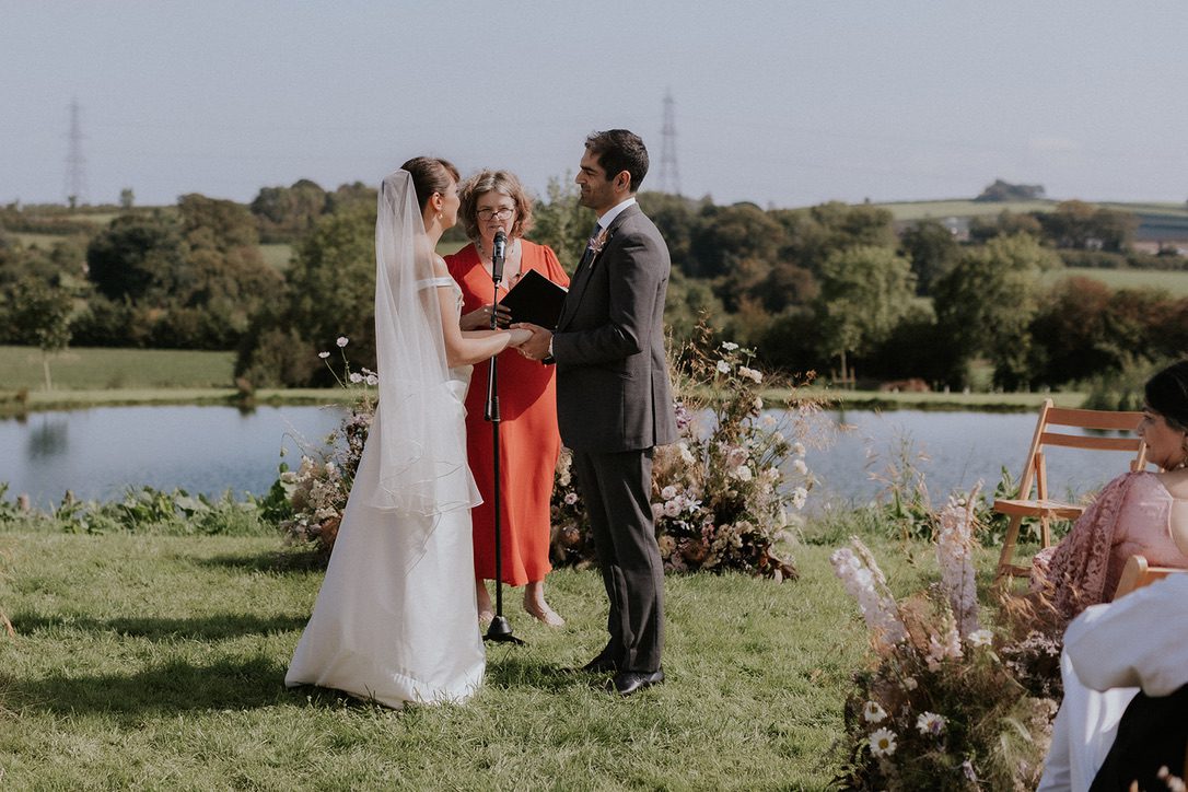 do registrars offer personal ceremonies like this outdoor wedding by a lake, held by a wedding celebrant
