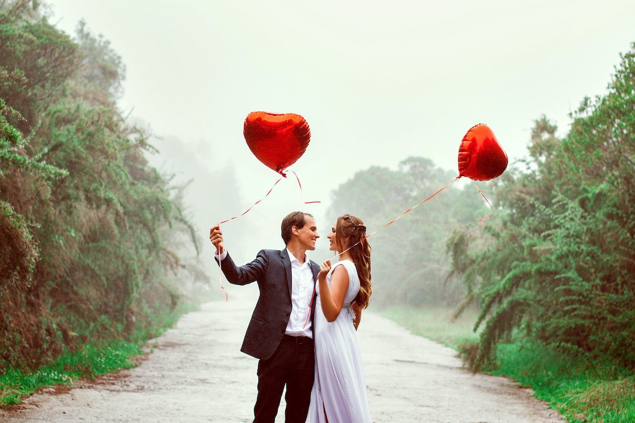 Valentine's Day Wedding bride and groom outside carrying red heart balloons