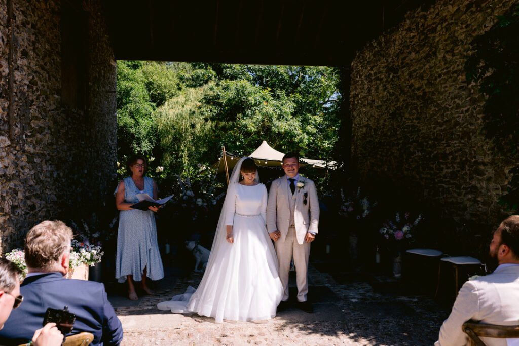 ng at home - Grace and Elijah under a walled bridge in courtyard with guests watching on