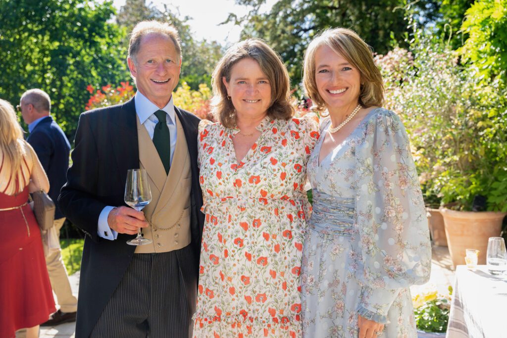 a couple with fanfare ceremonies man in morning coat lady in beautiful grey dress in sunny garden vow renewals