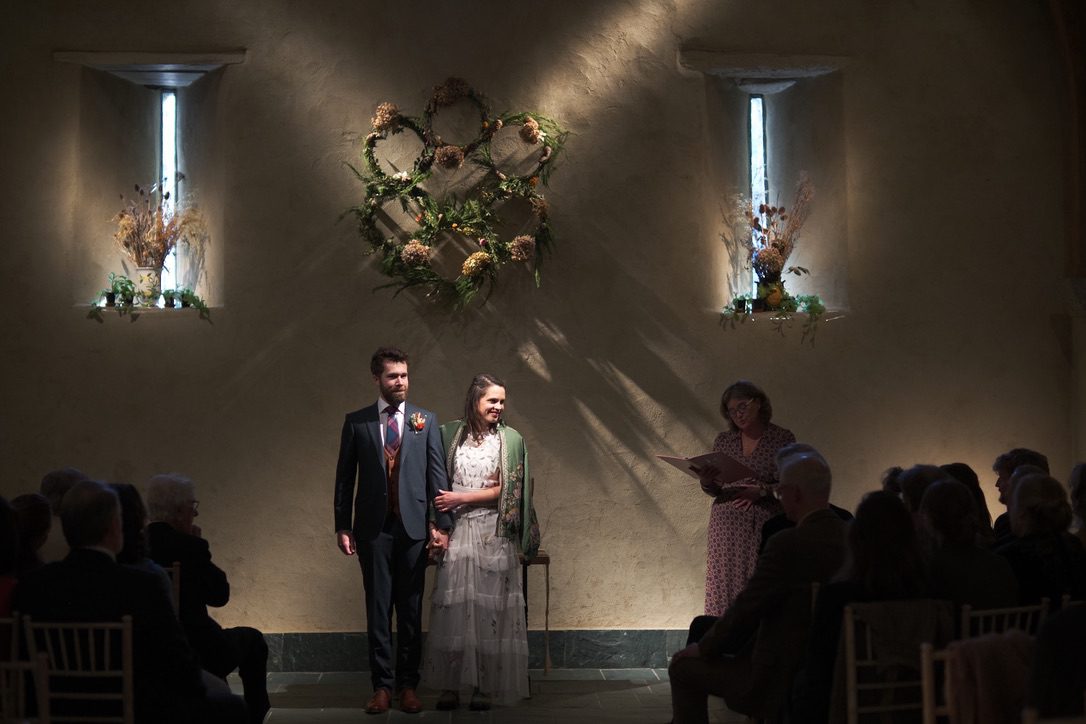 Atmospheric image of the great barn interior with bride and groom lit up beautifully by clever lighting
