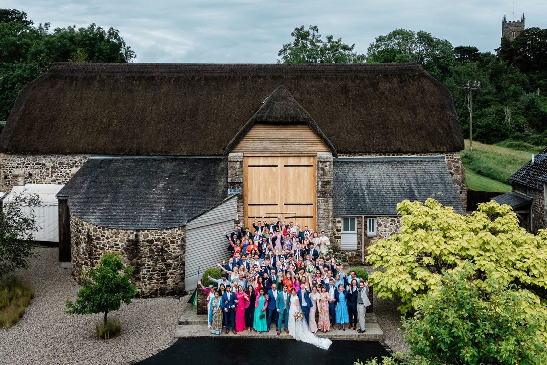all the guests standing outside the massive oak doors of The Great Barn