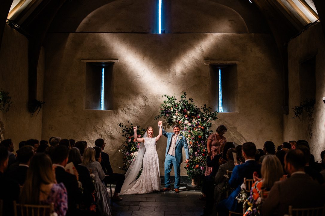 Megan & Sim – The Great Barn bride and groom celebrating at end of ceremony in The Great Barn, in Devon