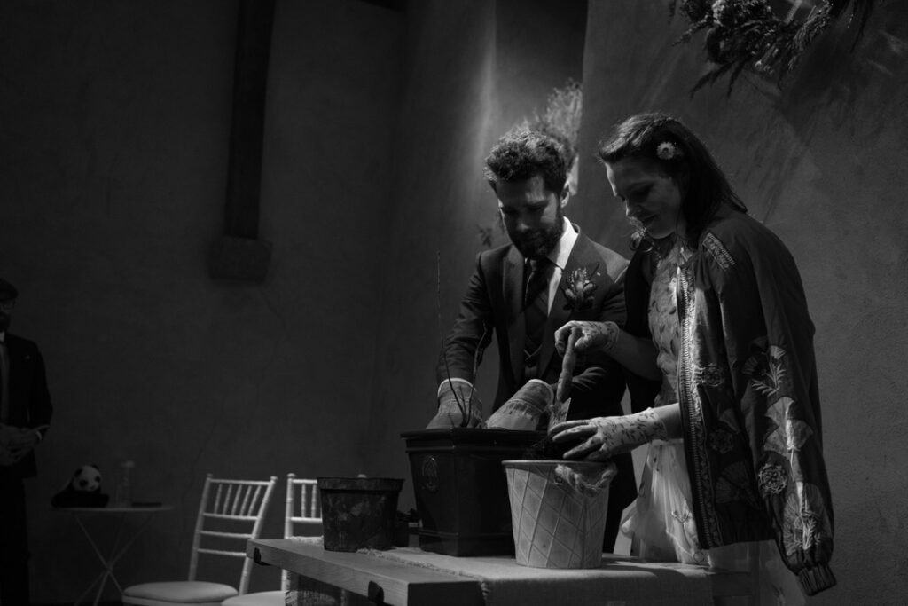 a black and white image showing bride and groom taking part in a planting ceremony 
