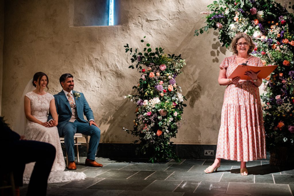 experienced wedding celebrant fan of fanfare ceremonies leading a ceremony at the great barn with bride and groom seated