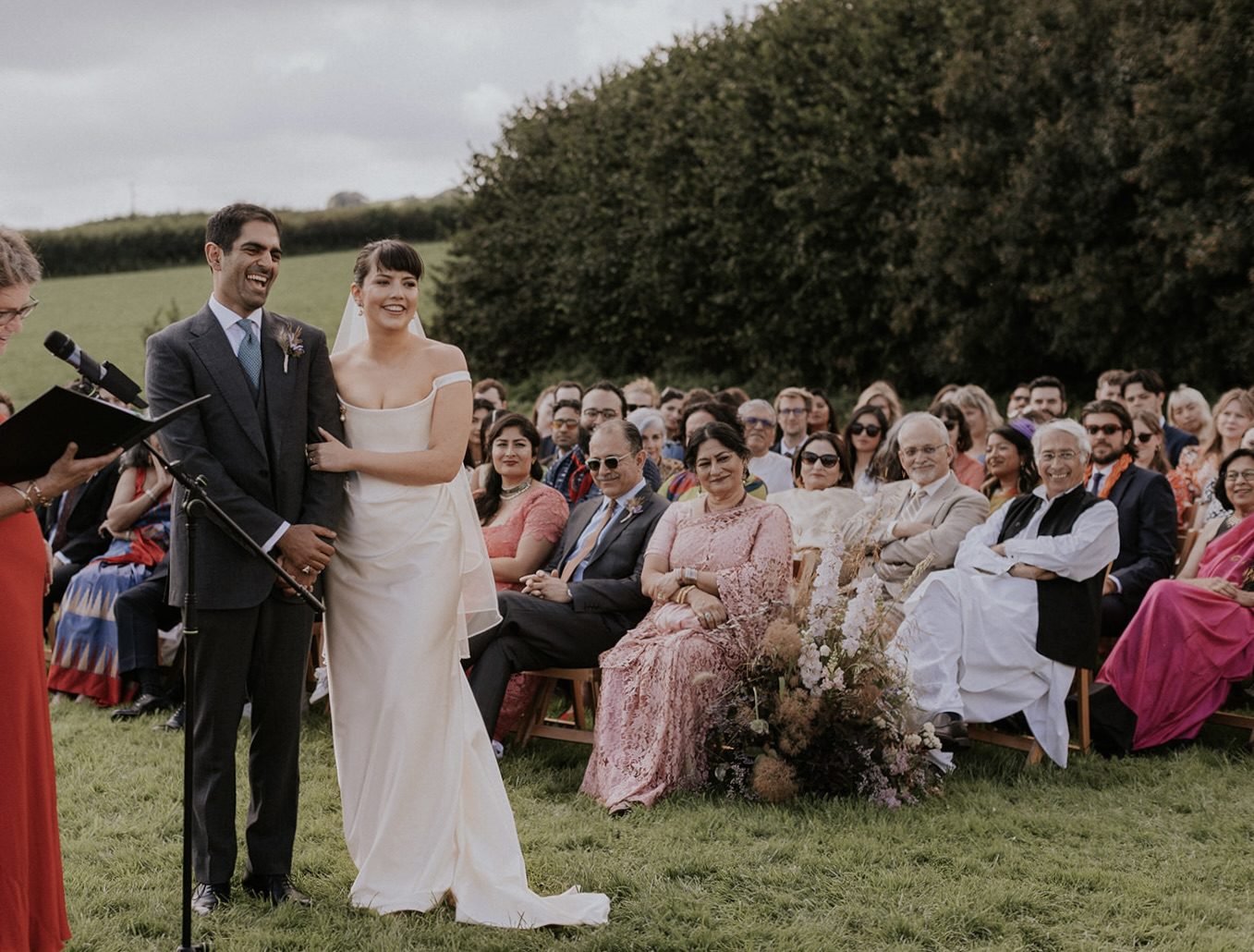bride and groom standing in front of their guests enjoying their wedding ceremony script at an outdoor ceremony