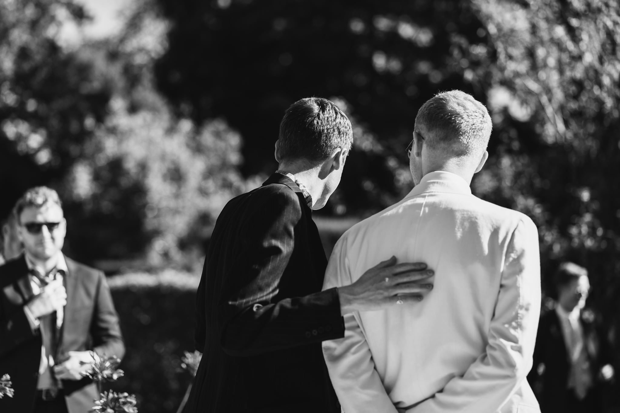 Black and White of a Groom and Best Man with their backs to the camera waiting for one of Fan's personal wedding ceremonies outside