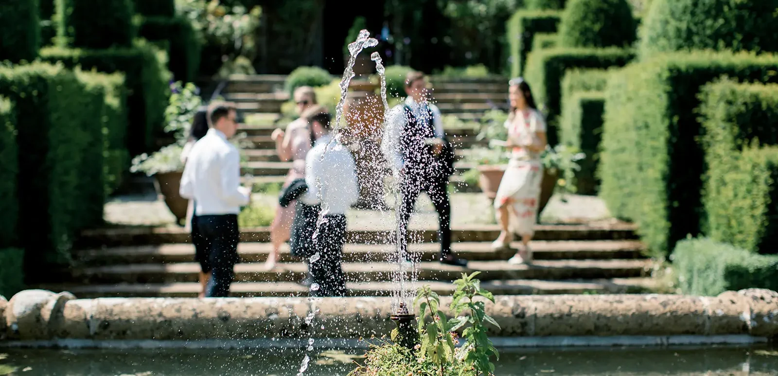 Guests at a celebrant wedding photographed through a water fountain