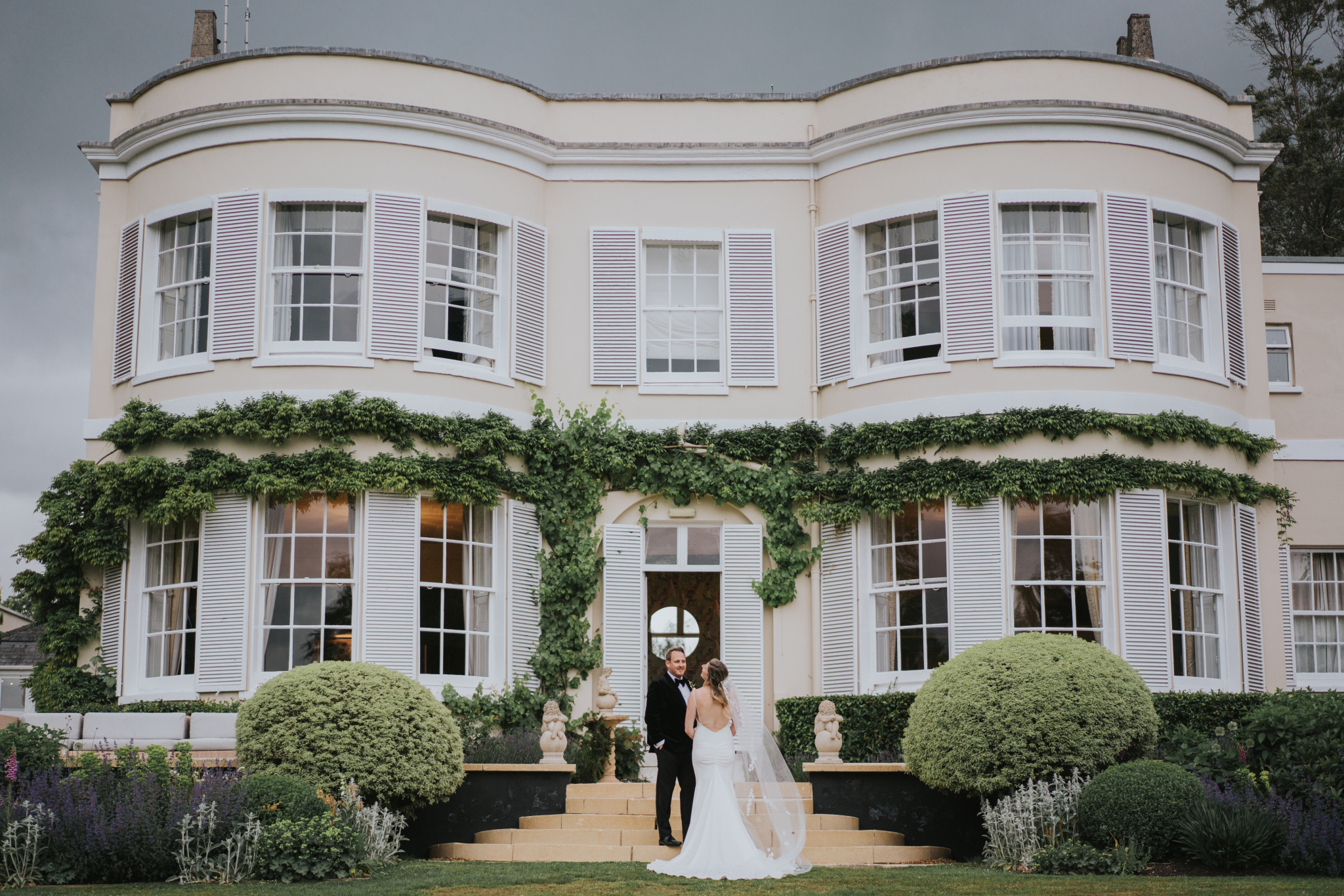 A bride and groom walking towards Deer Park Country House