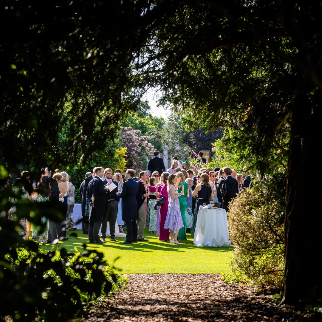 Guests mingle after a good ceremony in the estates gardens Guests mingling on a lawn surrounded by beautiful flowers after a good ceremony