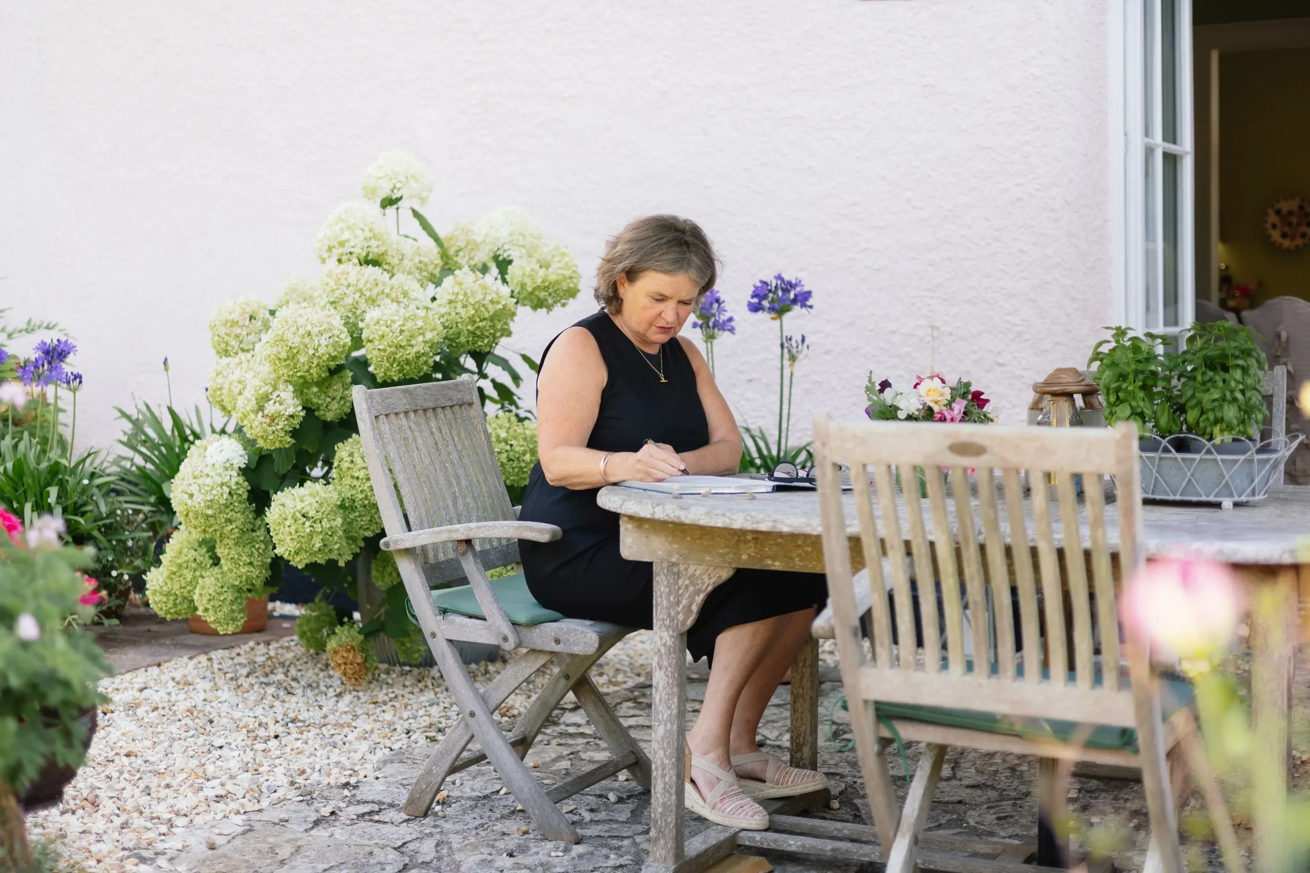 English wedding celebrant Fan sat writing at a wooden garden table
